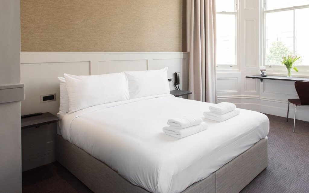 Sauberes Hotelzimmer mit gemachtem Bett und frischen Handtüchern.